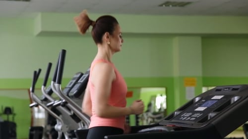 Woman Running on Treadmill for Fitness in Gym
