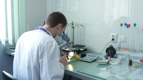 Young Man Using Microscope in Lab