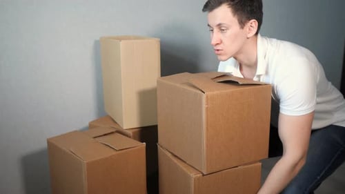 Man Stacking and Moving Cardboard Boxes at Home
