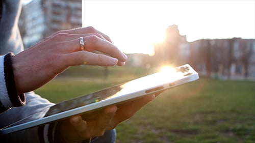 Man Uses Tablet on Sunset Background