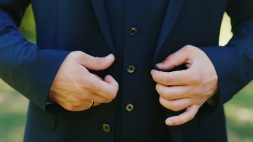 A Man In a Three-piece Suit Buttoning Outdoors