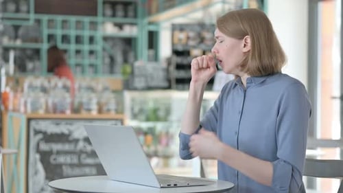 Young Woman Coughing While Using Laptop in Cafe