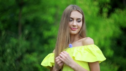 Beautiful Woman Holding a Flower in Green Setting
