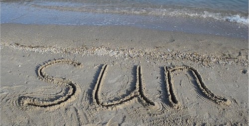 Word "Sun" Written in Sand on Beach