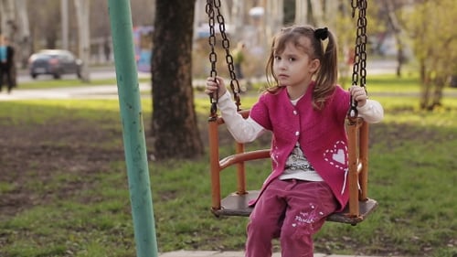 Petite fille triste se balançant sur une balançoire