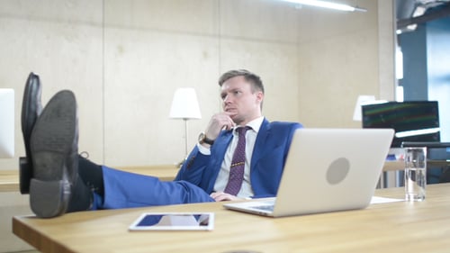 Young Adult Man Relaxing in Office with Feet Up