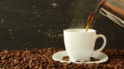 Coffee Being Poured into White Cup Among Beans