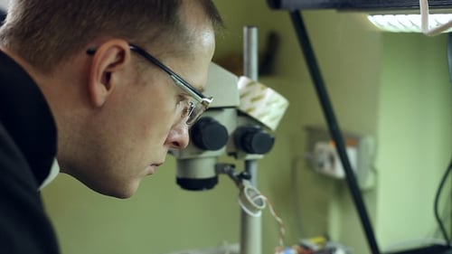 Man Focused on Technology Under Microscope in Lab