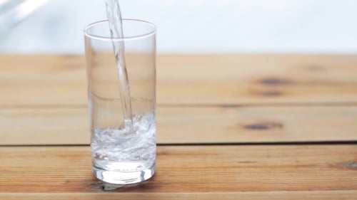Clear Liquid Being Poured Into Glass on Table