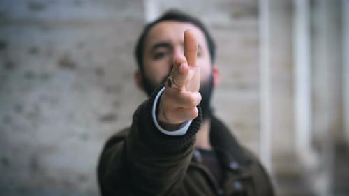 defokussierter Mann macht die Geste, um die Waffe mit den Händen auf die Kamera zu richten
