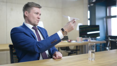 Businessman Launches Paper Airplane in Office