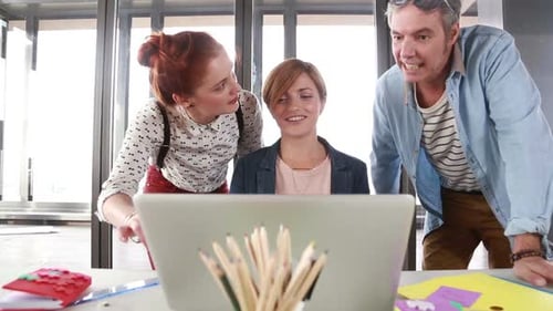 Creative Team Collaborating on Laptop in Modern Office