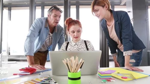 Three Coworkers Collaborate on a Laptop in Office