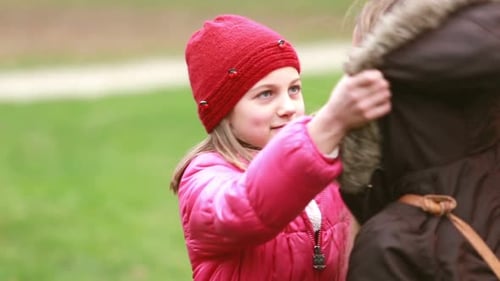 Mama setzt der Tochter eine Kappe auf den Kopf und küsst sie auf die Stirn 2