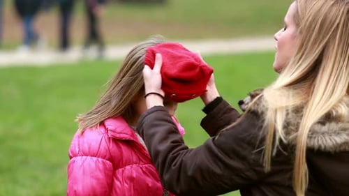 Mama setzt der Tochter eine Kappe auf den Kopf und küsst sie auf die Stirn 3