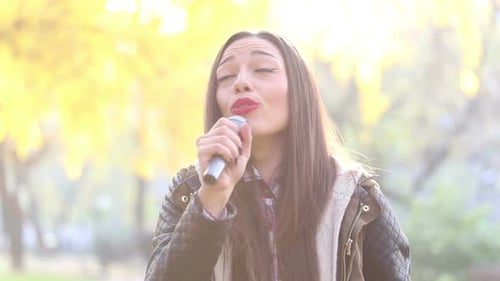Young Woman Singing With Microphone in Park