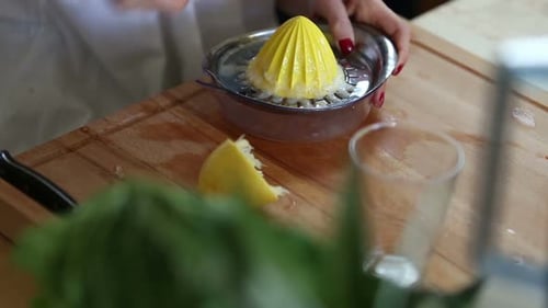 Close-Up Of Squeezing Lemon And Pouring Lemon Juice Into Glass