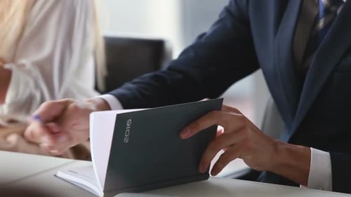 Attraktiver Geschäftsmann schreibt während eines Meetings in Notizbuch