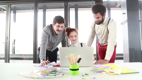Team Collaborates on Laptop in Modern Office Space