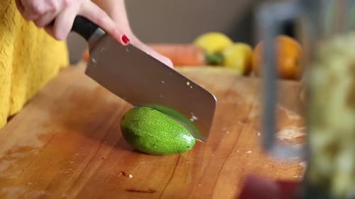 Woman Cutting Avocado on a Wooden Cutting Board