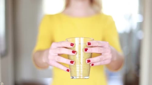 Woman Holding Healthy Green Smoothie Drink Indoors