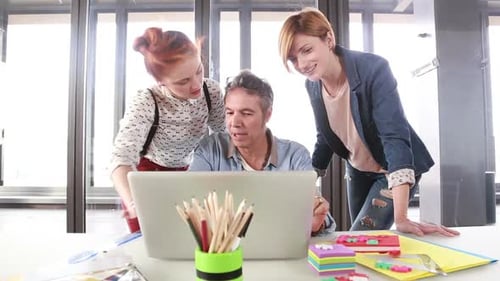 Team Collaborates Using Laptop in Office