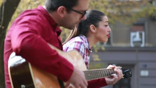 Schöne Frau singt, während gutaussehender Mann Gitarre spielt 2