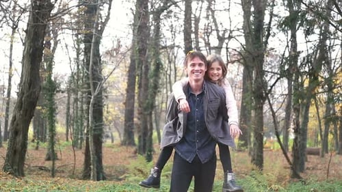 Father Giving Daughter Piggyback Ride in Autumn Park