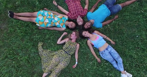 Cheerful Friends Lying in Circle on Green Grass