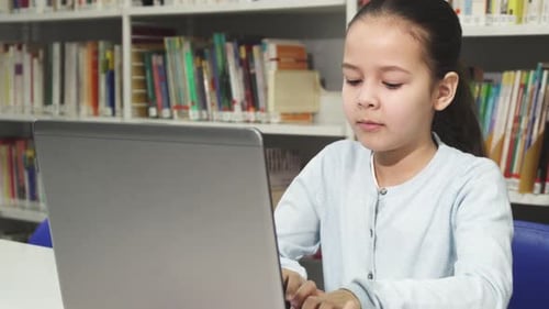 Focused Girl Using Laptop in School Library