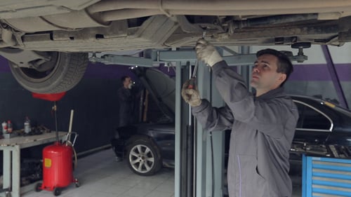 Homme vérifiant le fond de la voiture