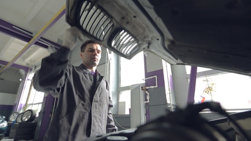 Mécanicien automobile ouvrant le capot de la voiture et vérifiant le niveau d'huile