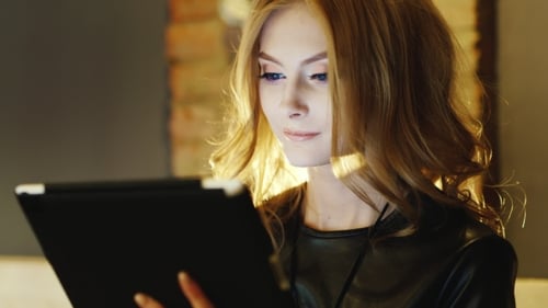 Beautiful Young Woman Enjoying The Tablet In a Cafe