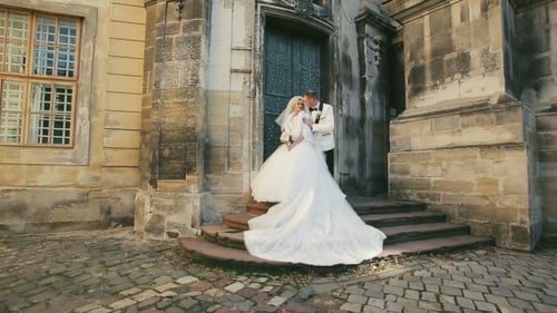 Happy Couple Posing By Historic Building On Wedding Day