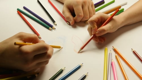 People Drawing Together with Colored Pencils on White Tabletop