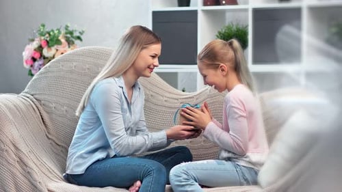 Happy Woman Giving Gift to Child on Couch
