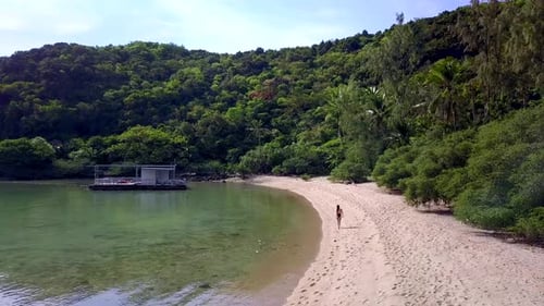 Linda mulher em traje de banho preto andando sozinha na praia na Tailândia