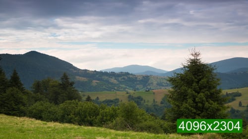 Vielschichtige Wolken über bewaldeten Bergen