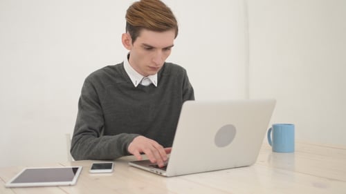 Young Adult Typing on Laptop at Desk