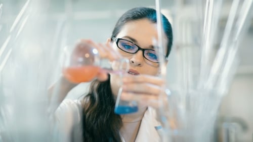 Female Scientist Holding Beakers in a Laboratory
