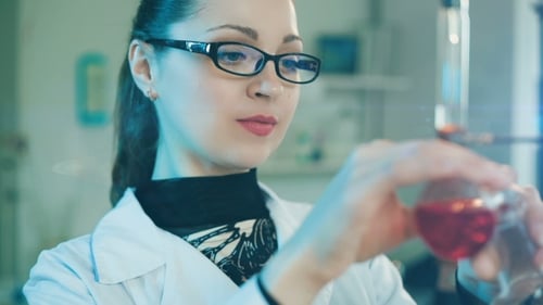 Woman Scientist Inspecting Red Liquid in Lab