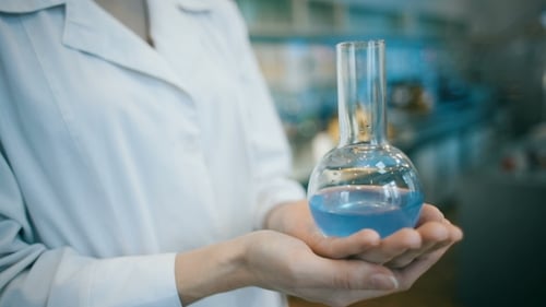 Scientist Holding Flask with Blue Liquid Close Up