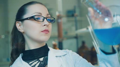 Woman Analyzing Blue Liquid in Flask in Lab