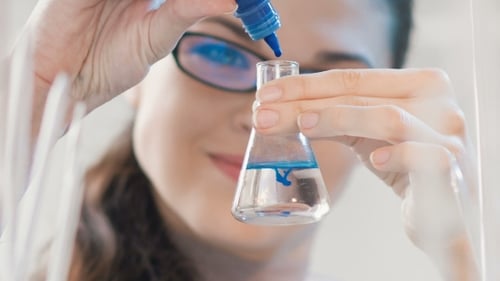 Young Adult Woman Adding Liquid to Beaker