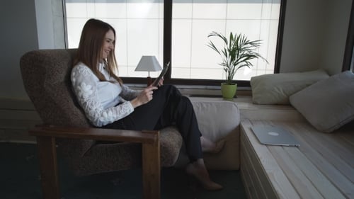 The Middle - Aged Woman Talking On The Tablet And Emotionally Gesticulates At Home