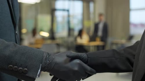 Gloved Hands Shake in a Modern Office