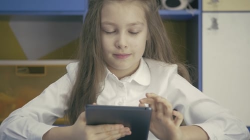 Cute Little Girl Studying At The Library Doing Homework With Tablet PC