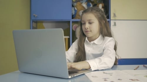 Young Girl Using a Laptop And Doing Homework In School