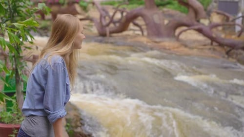 Woman Enjoying Flowing Waterfall in Nature Setting
