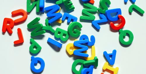 Colorful Plastic Letters Falling onto White Surface